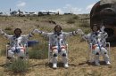 In this photo released by China's Xinhua news agency, Chinese astronauts, from left, Liu Wang, Jing Haipeng and Liu Yang, wave after coming out of the re-entry capsule, right, of Shenzhou-9 spacecraft in Siziwang Banner of north China's Inner Mongolia Autonomous Region Friday, June 29, 2012. The Chinese astronauts emerged smiling from the capsule that returned safely to earth Friday from a 13-day mission to an orbiting module that is a prototype for a future space station. (AP Photo/Xinhua, Wang Jianmin) NO SALES