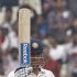 India's captain Dhoni raises his bat to celebrate his half-century on the second day of their second test cricket match against West IndiesÕ in Kolkata