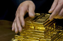 FILE - In an Oct. 17, 2011, file photo a staff member displays gold bullion bars during a news conference at the Chinese Gold and Silver Exchange Society in Hong Kong. A new study based on observations from space suggests the gold on Earth came from colliding dead stars in a cataclysmic event that occurred long ago. The research by the Harvard-Smithsonian Center for Astrophysics will appear in a future issue of the Astrophysical Journal Letters. (AP Photo, File)