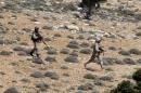 Lebanon's Hezbollah fighters walk with their weapons in Khashaat, in the Qalamoun region after they advanced in the area