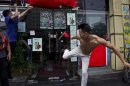 A man kicks the door of a Japanese pub decorated with Chinese national flags during a protest on the 81st anniversary of Japan's invasion of China, in Shenzhen
