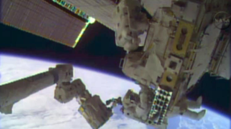 In this image taken from video provided by NASA, astronauts Rick Mastracchio, top, and Michael Hopkins work to repair an external cooling line on the International Space Station on Monday, Dec. 24, 2013, 260 miles above Earth. The external cooling line — one of two — shut down Dec. 11. The six-man crew had to turn off all nonessential equipment, including experiments. (AP Photo/NASA)