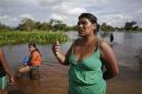 A woman speaks along a flooded street on the outskirts of Trinidad