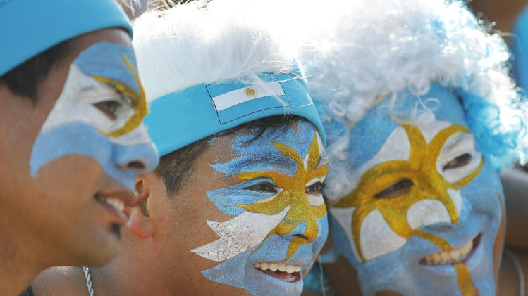 Argentina soccer fans, their faces painted to represent their country&#39;s national flag, pose for a photo during a live telecast of the World Cup group F match between Nigeria and Argentina, inside the FIFA Fan Fest area on Copacabana beach, in Rio de Janeiro, Brazil, Wednesday, June 25, 2014. Argentina won 3-2. (AP Photo/Leo Correa)