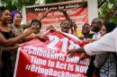 Members of the #BringBackOurGirls (#BBOG) campaign react on the presentation of a banner which shows "218", instead of the previous "219", referring to kidnapped Chibok school girls, during a sit-out in Abuja