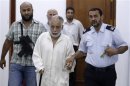 Deposed Libyan leader Muammar Gaddafi's former prime minister Al Baghdadi al-Mahmoudi is escorted in the office of his prison guard in Tripoli after being extradited from Tunis
