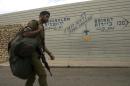 An Israeli soldier walks past a sign at the Israel-Lebanon border crossing in Rosh Hanikra, on May 6, 2013