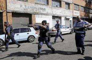 Police officers fire rubber bullets as they disperse African immigrants who are carrying machetes in Johannesburg