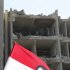 A national flag with a picture of Syria's President Bashar al-Assad is seen at the site of an explosion in an intelligence building in Damascus