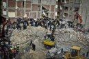 Egyptians stand in rubble after an eight story building collapsed in Alexandria, Egypt, Wednesday, Jan. 16, 2013. Egypt's official MENA news agency says two people have been killed. It was not immediately known what caused the building to collapse, but violations of building specifications have been blamed in the past for similar accidents. (AP Photo)