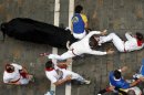 A runner is caught between the horns of an El Pilar fighting bull during the sixth running of the bulls of the San Fermin festival in Pamplona