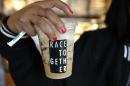 FILE - In this March 18, 2015 file photo, Larenda Myres holds an iced coffee drink with a "Race Together" sticker on it at a Starbucks store in Seattle. Starbucks baristas will no longer write "Race Together" on customers' cups starting Sunday, ending as planned a visible component of the company's diversity and racial inequality campaign that had sparked widespread criticism in the week since it took effect. (AP Photo/Ted S. Warren, File)