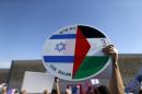 A demonstrator holds a sign with a Palestinian and Israeli flag during a demonstration by Palestinian and Israeli activists calling for a better future for both people, in the West Bank city of Bethlehem