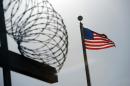 In this image reviewed by the US military, a US flag flies above a razorwire-topped fence at the "Camp Six" detention facility on December 10, 2008 at the US Naval Station in Guantanamo Bay, Cuba