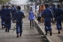 Woman passes by policemen during a protest against Burundi President Pierre Nkurunziza and his bid for a third term in Bujumbura