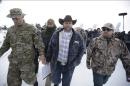 Ammon Bundy, center, one of the sons of Nevada rancher Cliven Bundy, walks off after speaking with reporters during a news conference at Malheur National Wildlife Refuge headquarters Monday, Jan. 4, 2016, near Burns, Ore. Bundy, who was involved in a 2014 standoff with the government over grazing rights told reporters on Monday that two local ranchers who face long prison sentences for setting fire to land have been treated unfairly. (AP Photo/Rick Bowmer)