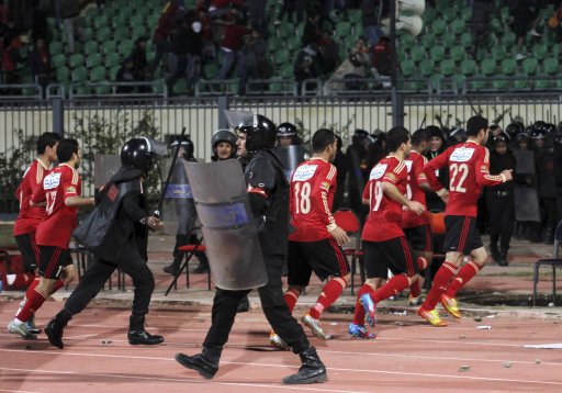 Riot police guard Al Ahli soccer players as they flee Port Said Stadium