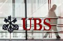 A man walks past a logo of Swiss bank UBS in Zurich