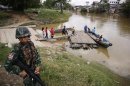 A soldier stands guard on the Thai side of the river as people prepare to cross into Malaysia in Sungai Kolok in southern Narathiwat province