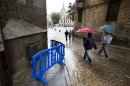 Varias personas pasan junto a la zona de la fachada de la Catedral de Toledo donde hoy ha caído una piedra, que ha rozado a una turista que no ha sufrido daños físicos, debido a las fuertes lluvias que han provocado el desprendimiento. EFE