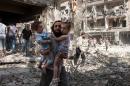 A Syrian man carries two girls through the rubble following a barrel bomb attack on the rebel-held neighbourhood of al-Kalasa in the northern Syrian city of Aleppo on September 17, 2015