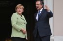 Greece's Prime Minister Antonis Samaras, right, and Germany's Chancellor Angela Merkel speak before their meeting at the Maximos mansion in Athens, Tuesday, Oct. 9, 2012. Amid draconian security measures and a mass protest, German Chancellor Angela Merkel arrived Tuesday for her first visit to Greece since the eurozone crisis began there three years ago. Her five-hour stop is seen by the Greek government as a historic boost for the country's future in Europe, but by protesters as a harbinger of more austerity and hardship. (AP Photo/Thanassis Stavrakis, Pool)