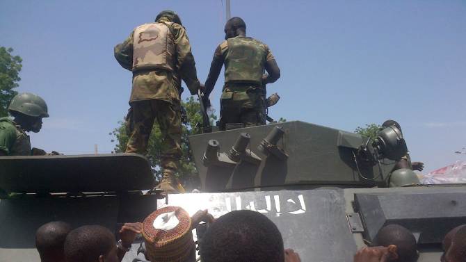 Troops stand on an armored personnel carrier (APC) recovered from Boko Haram insurgents in Konduga on September 16, 2014