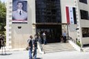 Journalists and security personnel stand in front of Yousef al-Azma military hospital during visit by team of United Nations chemical weapons experts in Damascus