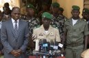 Coup leader Capt. Amadou Haya Sanogo, center, is accompanied by Burkina Faso Foreign Affairs Minister Djibril Bassole, left, as he addresses the media at junta headquarters in Kati, outside Bamako, Mali, on Sunday, April 1, 2012. The leader of Mali's recent coup says he is reinstating the nation's previous constitution amid international pressure to restore constitutional order. Sanogo said a national convention would be held to organize elections, but he did not announce a timeline for the elections. (AP Photo/Rebecca Blackwell)