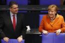 Economy Minister Gabriel talks to Chancellor Merkel at the lower house of parliament Bundestag in Berlin