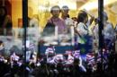 File photo of people looking on from inside a shopping mall as thousands protest against the amnesty bill in Bangkok's central business district