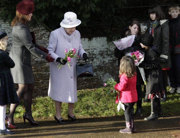 Britain's Queen Elizabeth II, center, receives flowers from children after she and other members of the royal family attended a Christmas Service at St Mary's church in the grounds of Sandringham Estate, the Queen's Norfolk retreat, England, Sunday, Dec. 25, 2011. (AP Photo/Lefteris Pitarakis)