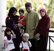 In this picture taken Saturday, June 4, 2011, Malaysian Muslim Ishak Md Nor, second from right, 40, and his two wives, Aishah Abdul Ghafar, left, 40, and Afiratul Abidah Mohd Hanan, 25, who are members of the "Obedient Wife Club," pose with their children after the club's launch in Kuala Lumpur, Malaysia. A Malaysian Muslim group has launched the "Obedient Wives Club" to teach women to be submissive and keep their spouses happy in the bedroom as a cure to social ills. (AP Photo)