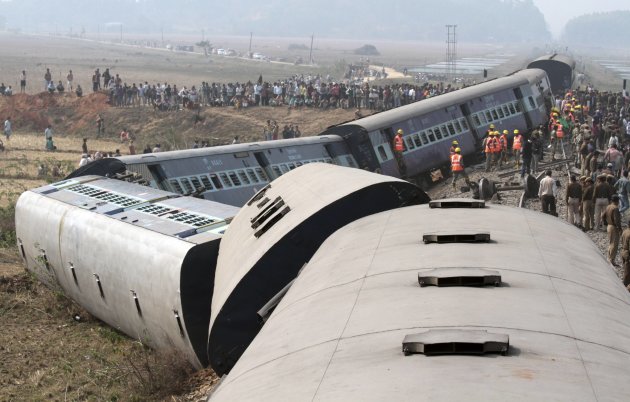 Onlookers and rescue workers gather around the derailed coaches of a passenger train in Bangapara village