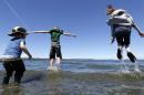 Ainsley MacDonald, right, and Will Walker, 10, try to leap above incoming waves as Calister MacDonald, left, 3, looks on Tuesday, July 1, 2014, at a beach on the Puget Sound in Mukilteo, Wash. Temperatures are expected to hit near 90 in nearby Seattle and 97 in Portland Tuesday, which is considered a heat wave in the Pacific Northwest in July. (AP Photo/Elaine Thompson)