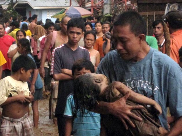 An unidentified father cries as he carries the body of his child, who was among hundreds killed by Typhoon Wasi in Cagayan de Oro southern Philippines