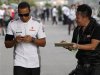 A fan asks McLaren Formula One driver Hamilton for an autograph as he walks in the paddock after the second practice session of the Japanese F1 Grand Prix at the Suzuka circuit