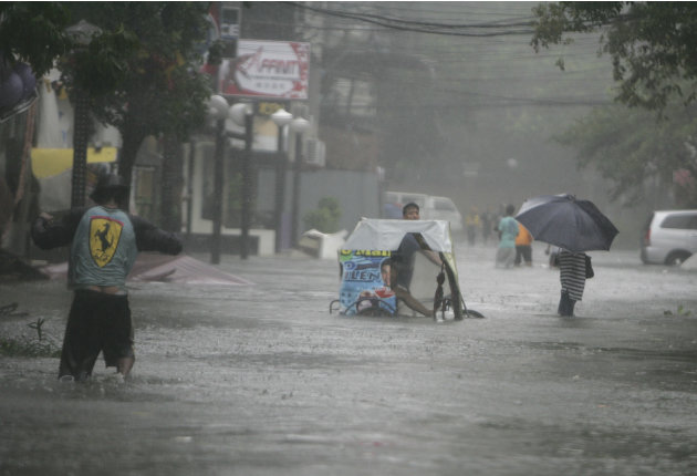 Commuters wade through a flooded street at the height of typhoon Nesat Tuesday Sept. 27, 2011 in Manila, Philippines. Massive flooding hit the Philippine capital on Tuesday as typhoon winds and rains 