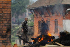Nepalese people stand beside the funeral pyre of a &hellip;