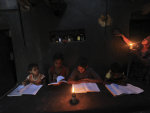 ADVANCE FOR SUNDAY JULY 3 AND THEREAFTER In this May 24, 2011 photograph, Boommi Gowda, extreme right , holds an oil lamp as her children study in their house in Nada village on the outskirts of ...