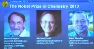 Um telão exibe as fotografias dos cientistas Martin Karplus, Michael Levitt e Arieh Warshel, os três vencedores do Prêmio Nobel de Química
