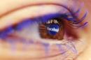 A Facebook logo reflected in the eye of a woman is seen in this picture illustration
