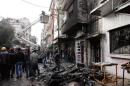 Syrians look at the damage after an alleged mortar attack by opposition forces on the al-Mahattah neighbourhood of Homs on January 9, 2014