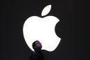 A man stands in front of an Apple logo in downtown Shanghai