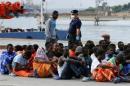 Migrants sit after they disembarked from the vessel Topaz Responder in the Sicilian harbour of Augusta