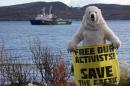 A Greenpeace activist dressed as a polar bear holds a banner in front of the Arctic Sunrise protest ship in Kola Bay, Murmansk, on September 24, 2013