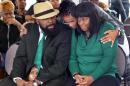Michael Brown Sr., left, and his wife, Calvina Brown, right, are embraced by Trina Moorehead, of Florissant, upon their arrival at the Flood Christian Church service that was held in a tent on Sunday, Nov. 30, 2014, in Country Club Hills, Mo. The church was among dozens of businesses damaged or destroyed by fires Monday night. (AP Photo/St. Louis Post-Dispatch, J.B. Forbes)