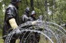 Hungarian soldiers put up spools of razor wire on Slovenian border in Zitkovci, Friday, Sept. 25, 2015. Hungary has installed spools of razor wire near a border crossing with Slovenia, which like Hungary is part of the EU's Schengen zone of passport-free travel. (AP Photo/Darko Bandic)
