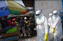 Red cross workers, wearing protective suits, carry the body of a person who died from Ebola, in Monrovia, on January 5, 2015