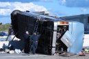 Indiana State Police investigators inspect the underside of a bus that crashed Saturday, July 27, 2013, on Indianapolis' far north side while carrying teenagers returning from a summer camp in Michigan. Three people were killed and 26 others were taken to local hospitals following the crash, which occurred when the bus exited an interstate ramp and crashed into a concrete retaining wall. Investigators don't yet know what caused the crash about a mile from its destination, Colonial Hills Baptist Church. (AP Photo/Rick Callahan).